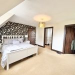 Cosy bedroom with patterned wallpaper and ensuite bathroom.