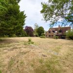 Spacious garden with brick house and trees.