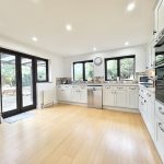Spacious modern kitchen with wooden floor and garden view.