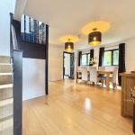 Modern dining room with wooden floor and staircase.