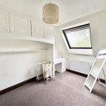 Empty room with slanted window and desk.