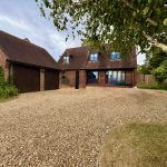 Red brick house with large gravel driveway.