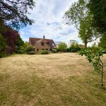 Large garden with brick house and trees.