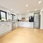 Modern kitchen with white cabinets and wooden floor.