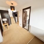 Modern hallway with staircase and wooden doors.