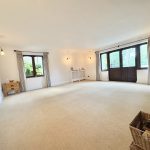 Spacious living room with large windows, light decor.