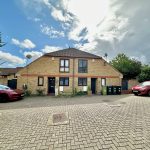 Brick house with parked cars, cloudy sky above.