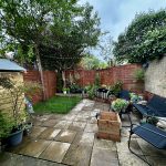 Cosy garden with seating and lush greenery.
