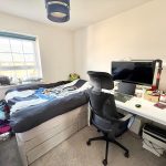 Modern bedroom with desk and computer setup.