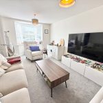 Modern living room with large TV and sofa.