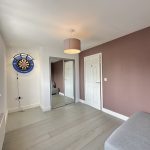 Room with dartboard and mirrored wardrobe.