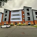 Modern apartment building with parked cars outside.
