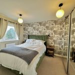 Chic bedroom with tropical wallpaper and modern decor.