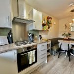 Modern kitchen with dining area and hanging lights.