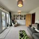 Cosy living room with large windows and bookshelf.