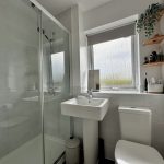 Modern bathroom with glass shower and window view.
