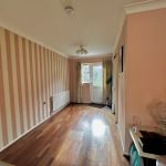 Empty room with striped wallpaper and wooden floor.