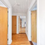Hallway with open wooden doors and white walls.