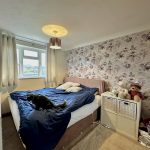 Cosy bedroom with floral wallpaper and plush toys.