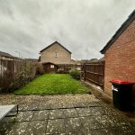 Backyard with patio, lawn, and garden shed on cloudy day.