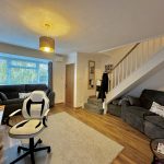 Living room with sofas, computer desk, and stairs.