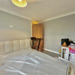 Bedroom with unassembled bed and cluttered table.