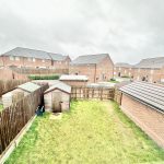 Residential backyard with wooden fence and sheds.