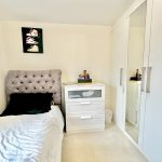 Minimalist bedroom with bed, dresser, and wardrobe.