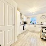 Modern kitchen with white cabinets and wooden flooring.