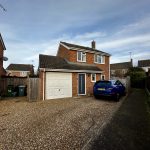 Two-storey brick house with blue car parked outside.