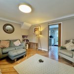 Cosy lounge with sofa, armchair, and standing lamp.