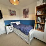 Child's bedroom with bed, bookshelf, and wall art.