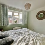 Cosy bedroom with green walls and large window.