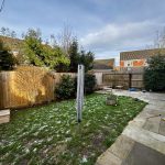 Residential garden with lawn, patio, and wooden fence.