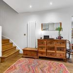Wooden staircase with rustic furniture in hallway.