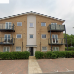 Modern residential building with balconies and parking spaces.