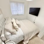 Cosy bedroom with TV on the wall.
