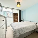 Modern bedroom with striped bedding and large window.