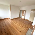 Empty room with wooden flooring and white walls.