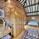 Rustic bedroom with exposed brick and wooden furniture.