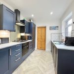 Modern kitchen with navy cabinets and wooden door.