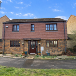 Two-storey brick house with brown roof, front garden.