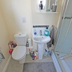 Compact bathroom with shower, sink, and toilet.