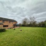 Large garden with brick house and conservatory.