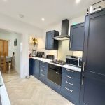Modern kitchen with navy blue cabinets and dining area.