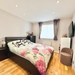 Modern bedroom with floral bedding and hardwood floor.