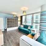 Modern apartment living room with teal sofas.