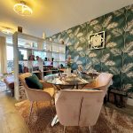 Modern dining room with tropical wallpaper and soft lighting.