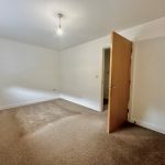 Empty room with beige carpet and open door.