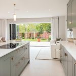 Modern kitchen with garden view through open doors.